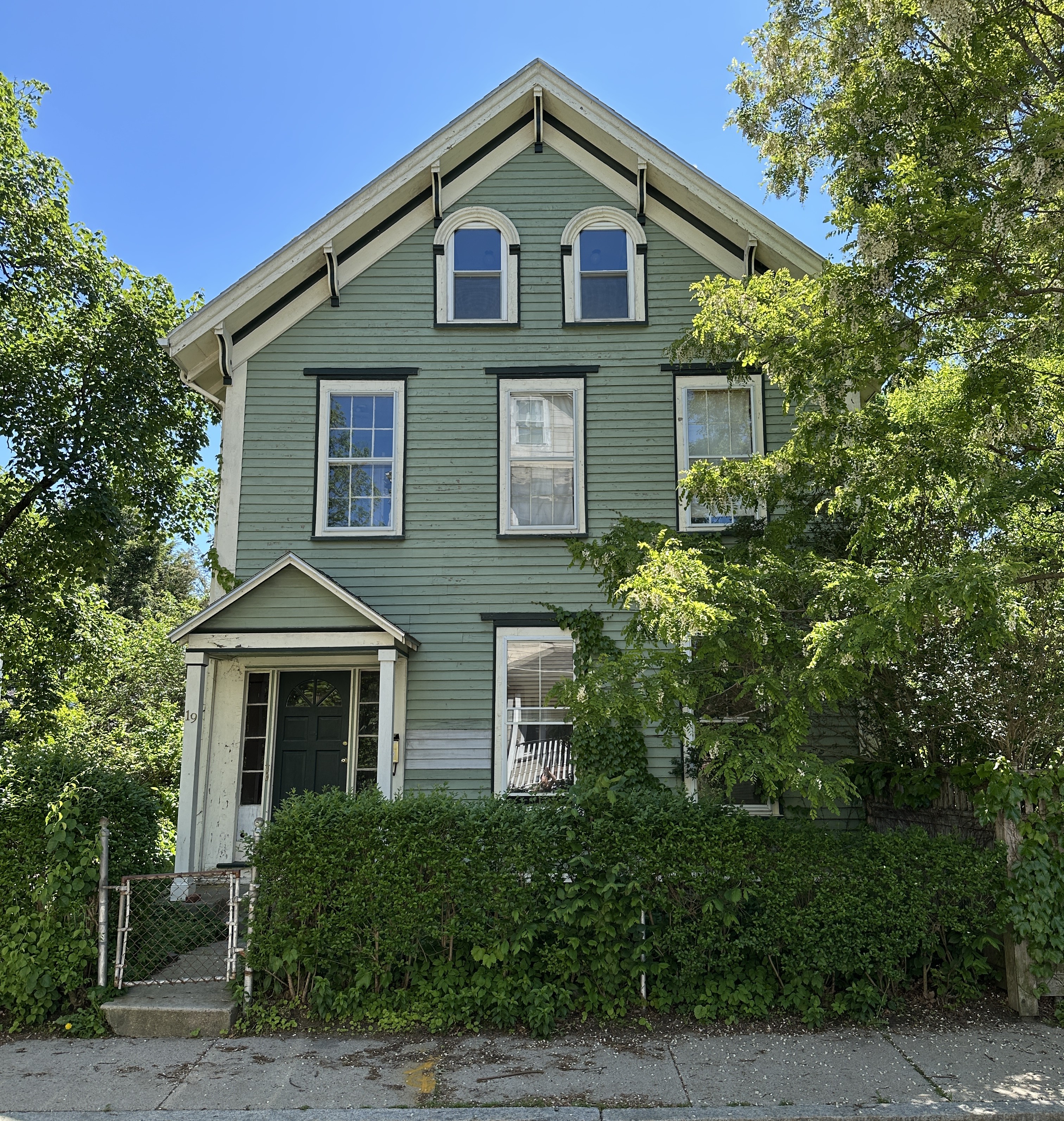 19 Kenton Road, Photo Credit: Matthew Dickey. A three story green house with a front gable and single bay front porch. It features Italianate details like cornice brackets and arched windows on the third floor.